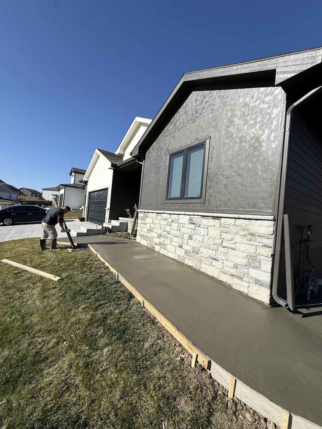 Freshly poured concrete walkway beside a stone-and-stucco home near Omaha