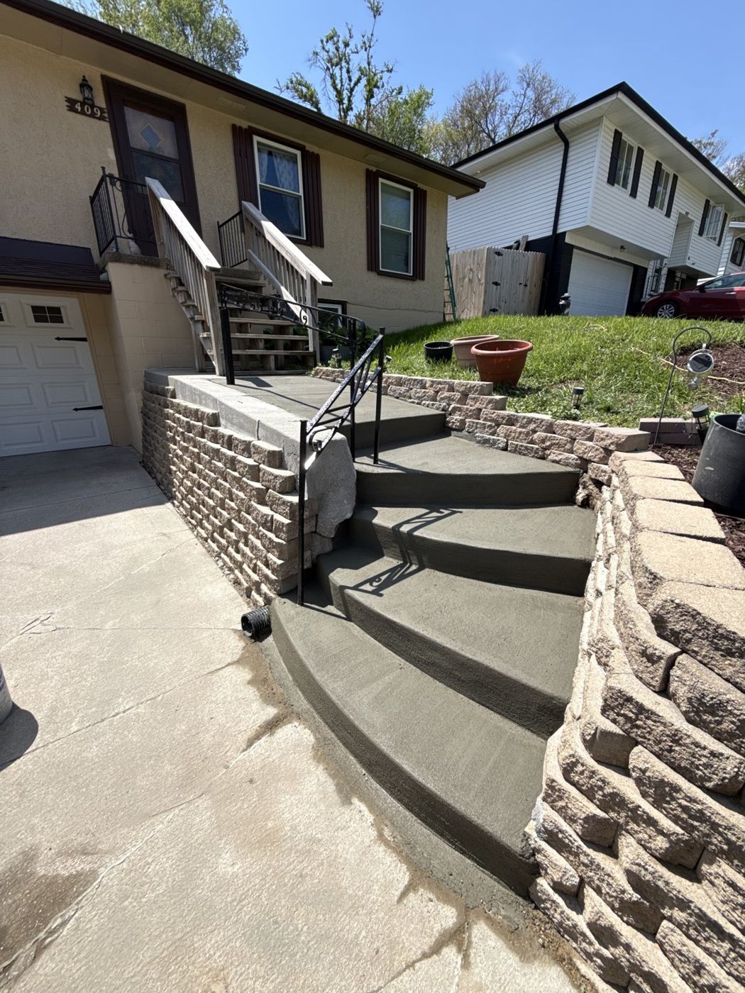 Completed stone retaining wall with new concrete steps near Omaha